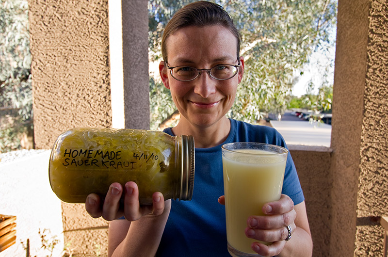 Caroline Wise holding a quart of fresh homemade sauerkraut and a glass of sauerkraut juice