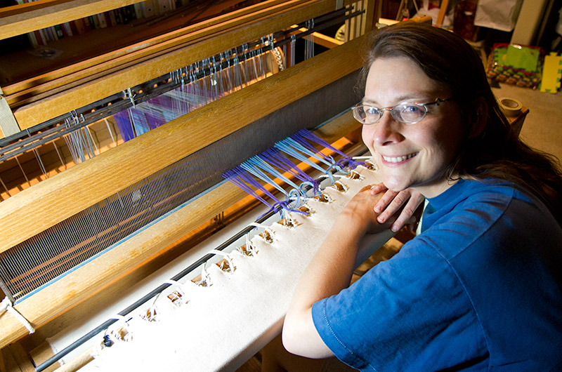 Caroline Wise sitting at her Counter Balance loom having just finished warping also known as dressing, the loom.