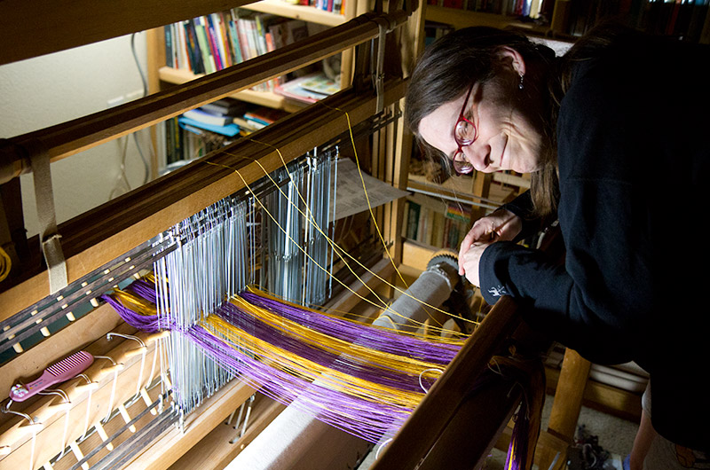 Caroline Wise threading her homemade 4-shaft counter balance loom