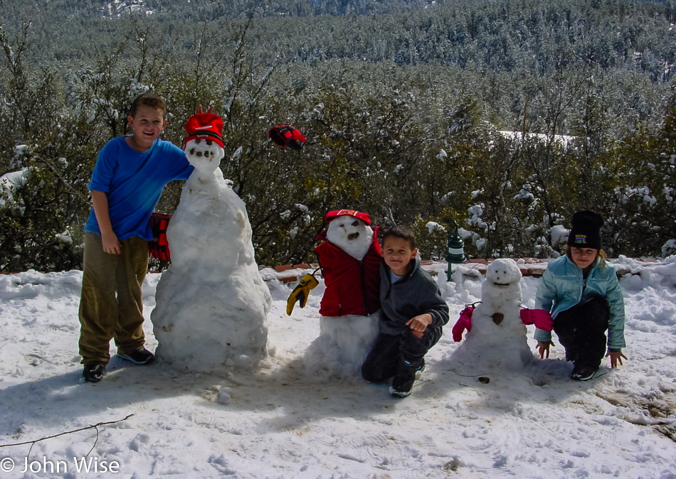 Conner, Keaton, and Tia Herman posing with their snowmen in Prescott, Arizona