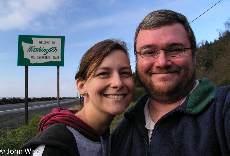 Caroline Wise and John Wise in front of the Welcome to Washington state sign