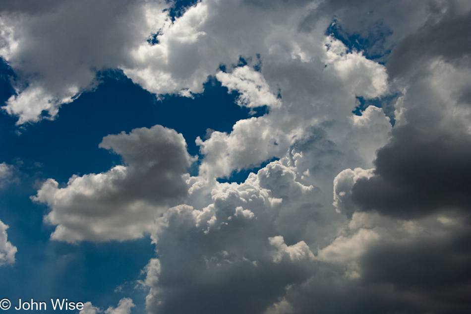 Heavy clouds move in with breaks that allow a glimpse of bright fluffy clouds contrasted against the deep blue sky