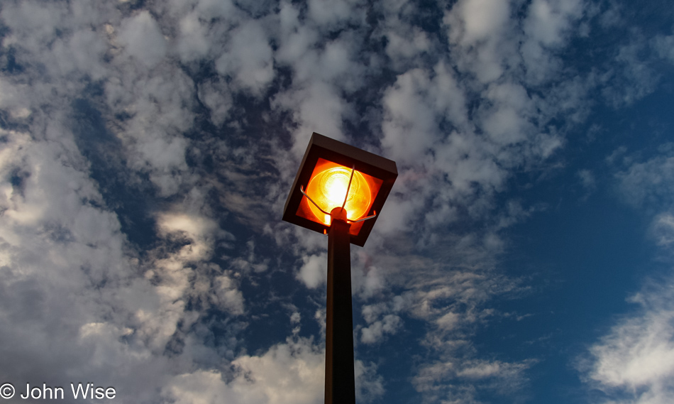 Parking lot lamp turning on early during late afternoon in Phoenix, Arizona