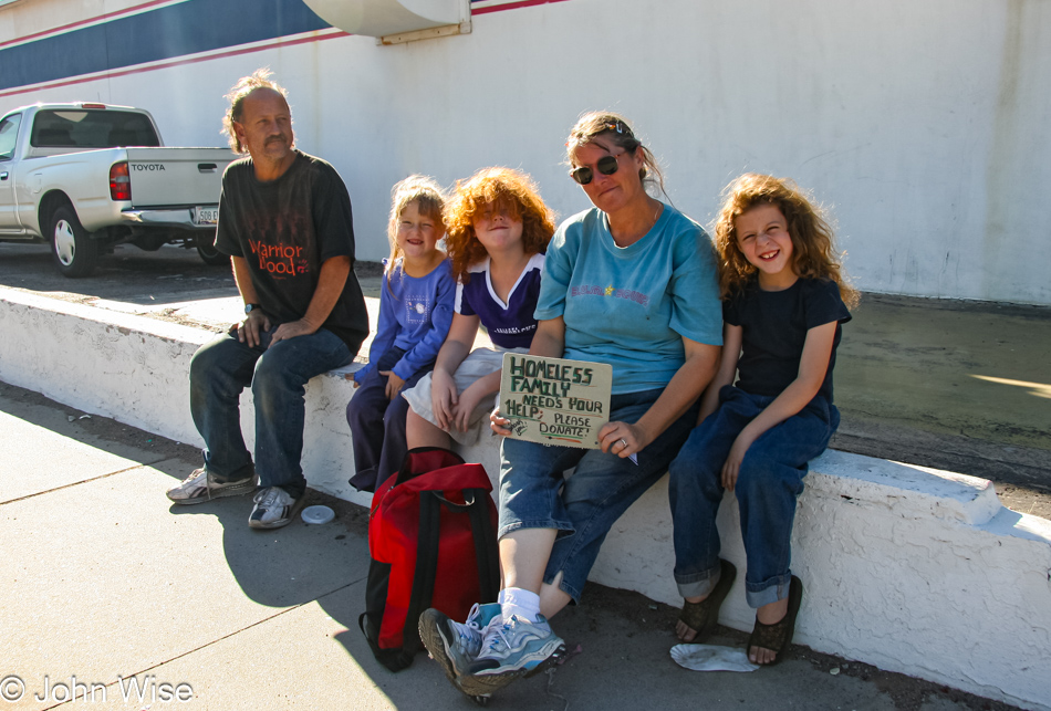 Needing a place to stay for the evening this family sits road side waiting for help under the 104 degree sun of summer in Phoenix, Arizona