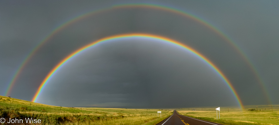 A full rainbow stretching from side to side across the landscape in northern Arizona west of Springerville