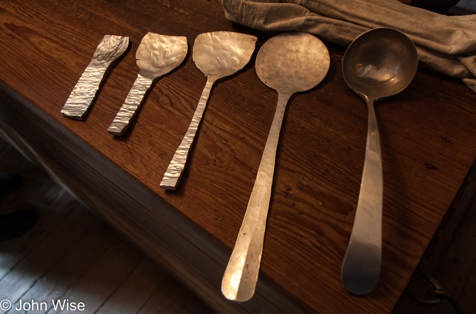 The different stages of a piece of silver that is being hammered into a ladle on display at the silversmith in Colonial Williamsburg, Virginia