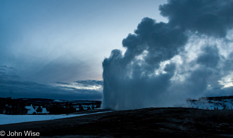 Old Faithful erupting at dusk on a winter day on the Upper Geyser Basin in Yellowstone National Park January 2010
