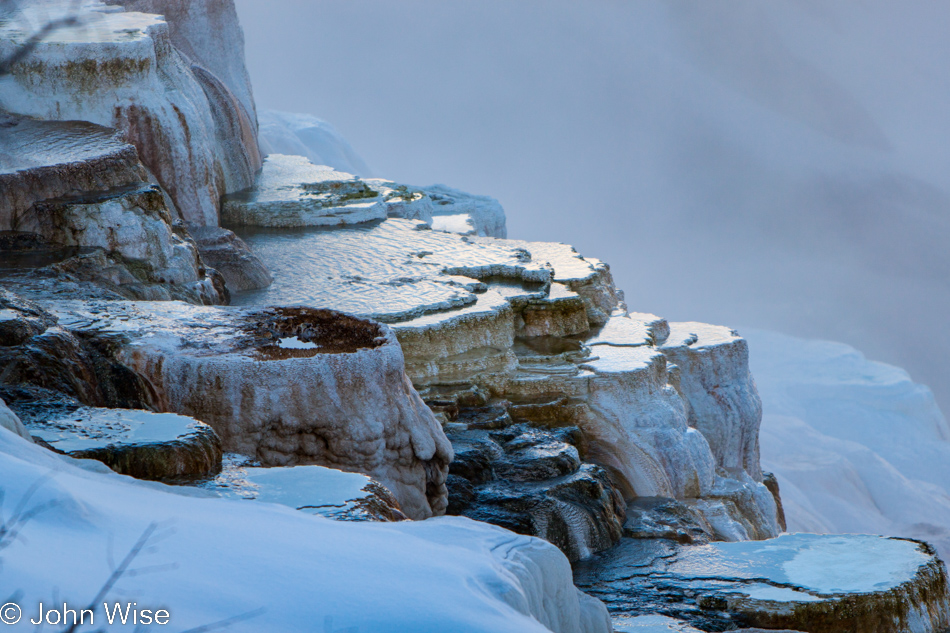 Pools of water surrounded by snow on the front of Canary Spring on the Upper Terrace at Mammoth Hot Springs in Yellowstone National Park January 2010