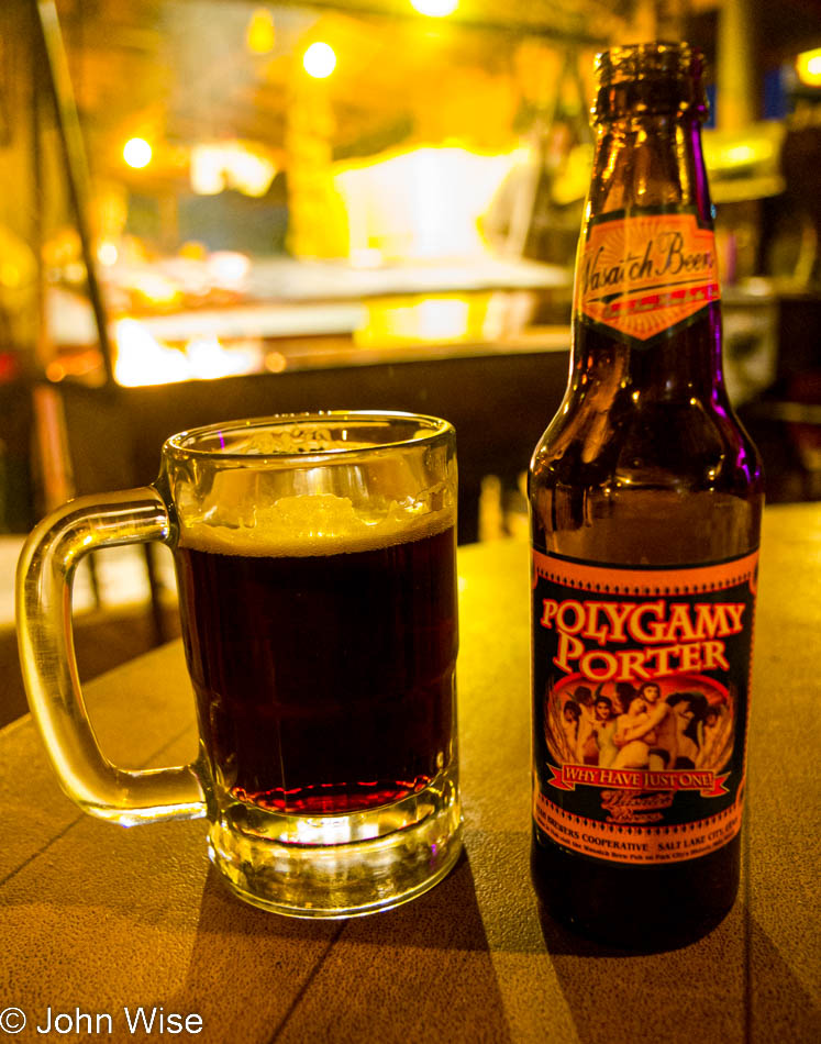 A bottle of Polygamy Porter beer with the swinging grill from the Mexican Hat Lodge in the background