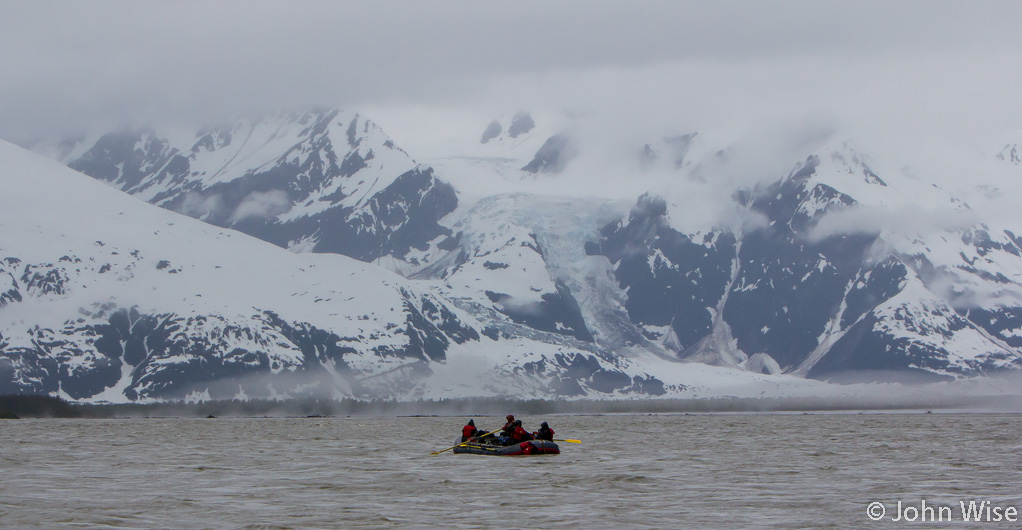 Snow covered mountains where the snow reaches the riverside on the Alsek River in Alaska