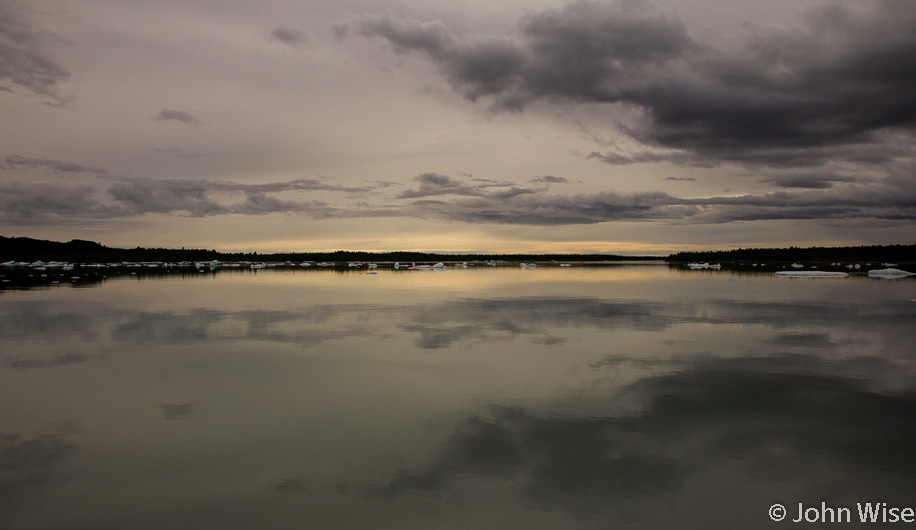 It's getting late in the day as golden light falls on Alsek Lake looking in the direction of the Pacific Ocean in Alaska