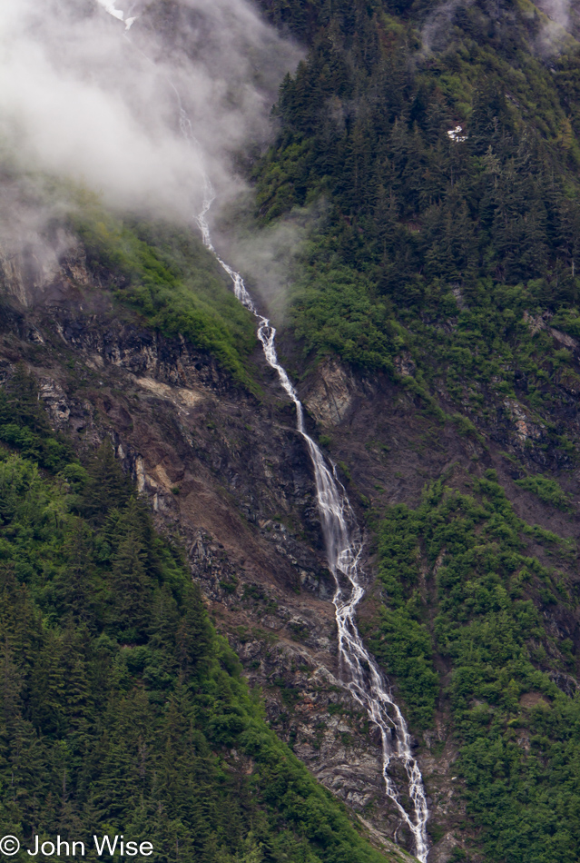A cascade peeks out from under the clouds near Juneau, Alaska