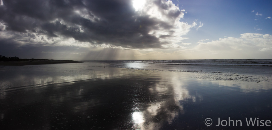 The sun getting low in the sky as it competes with the clouds over a beach on the Oregon coast