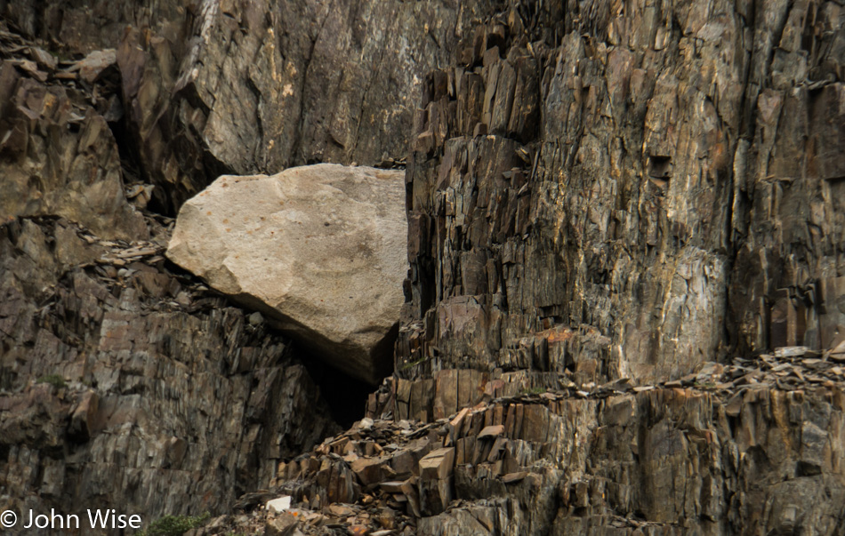 The white bit of rock is known as an "Erratic" in that it's obviously from a different area and was deposited by a glacier. On the Alsek in Yukon, Canada