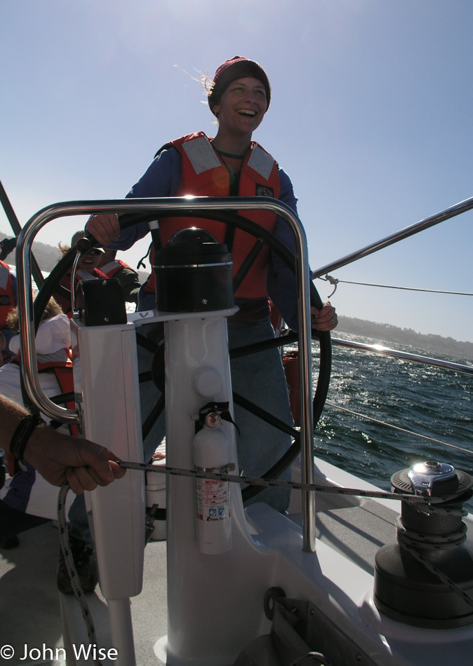 Caroline Wise at the helm of a sailboat in Monterey California